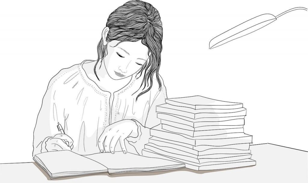 young female sits at her desk writing in her journal.