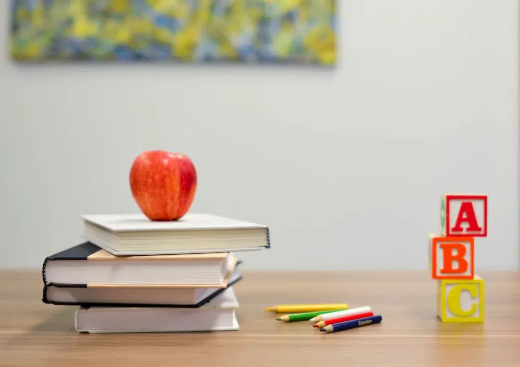 education concept - apple sitting on top of a pile of books on the table