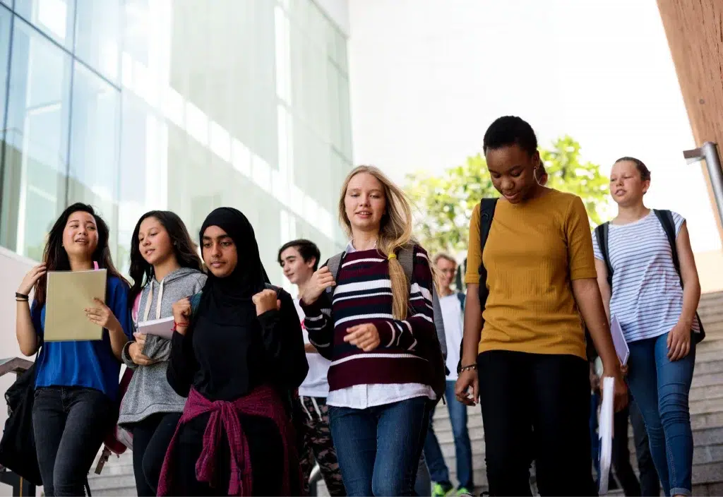 a diverse group of young females walking down the steps with their backpacks on