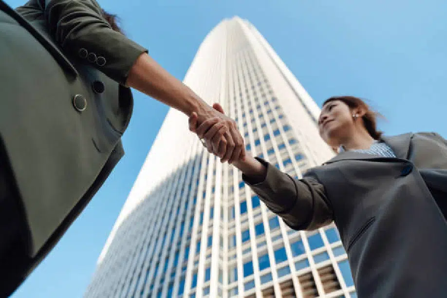 two people shaking hands with a skyscraper in the background