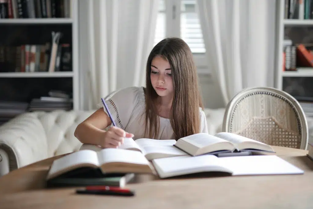 Young girl studying with books and notes at home in a cozy setting