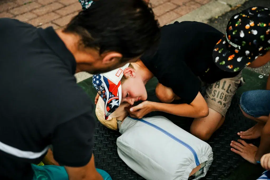 teenager engaged in a CPR course using dummy - listening for the life signs