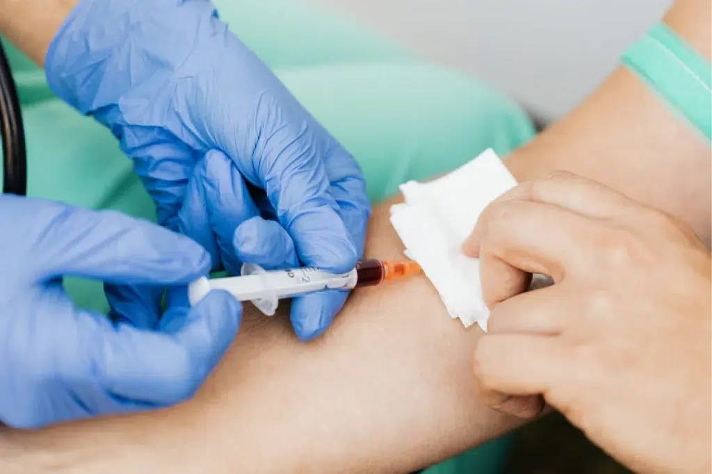 photo showing hands in blue medical gloves performing a blood draw