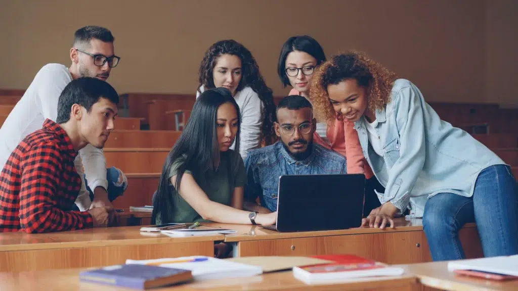 Diverse group of students gathered around a laptop
